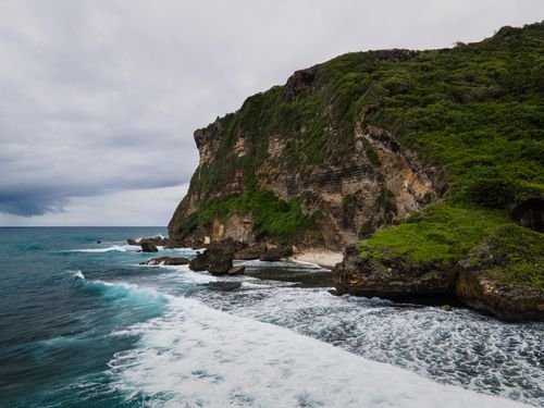 Free A stunning coastal scene with cliffs, lush greenery, and ocean waves crashing against rocks. Stock Photo