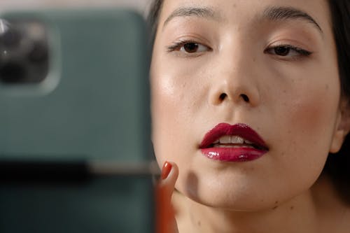 Free Close-Up Photo of a Woman in Red Lipstick Fixing Her Makeup Stock Photo