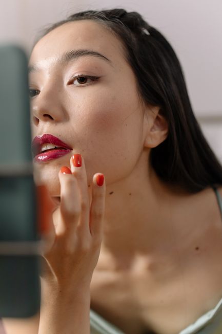 Asian woman applying lipstick — elegant beauty routine portrait