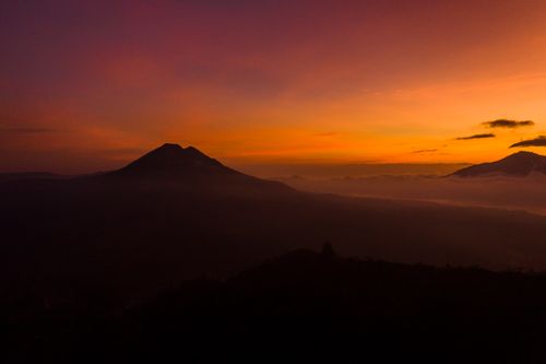 Free Silhouette of a mountain under a dramatic and colorful twilight sky. Stock Photo