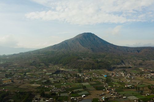 Free Stunning aerial shot of Mount Batur with vast agricultural fields below under a blue sky. Stock Photo