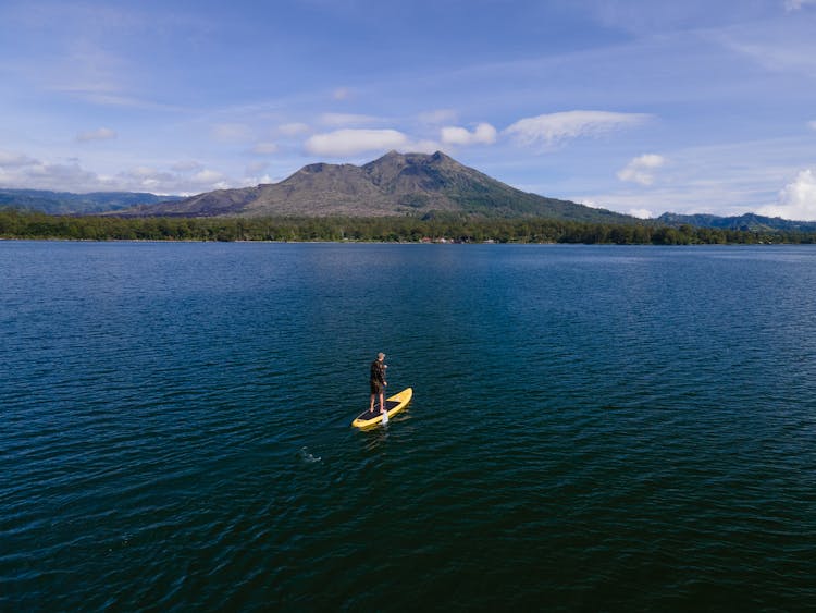 Person Paddleboarding In Calm Ocean 