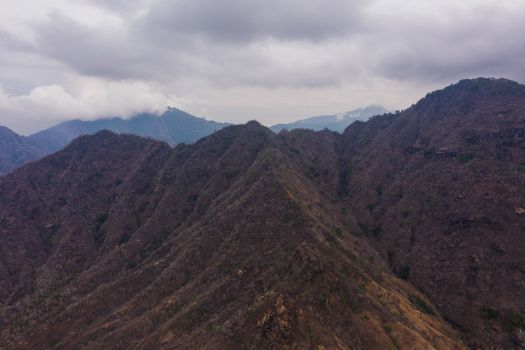 Stunning aerial shot capturing the natural beauty and scale of a mountain range under cloudy skies.