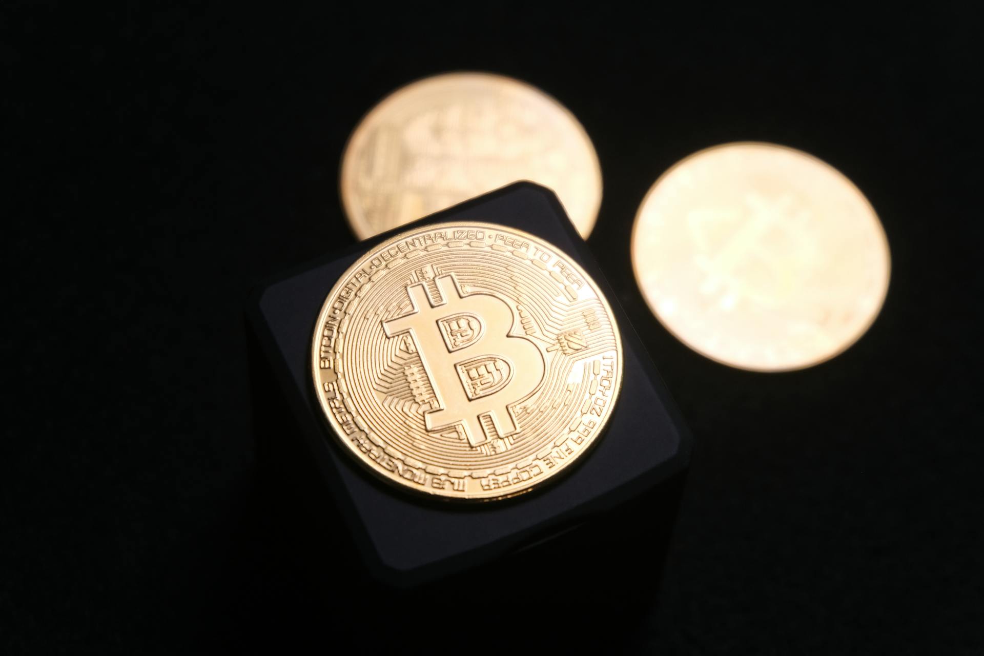 Close-up of golden Bitcoin coins on a sleek black background, emphasizing cryptocurrency themes.