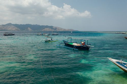 Free Scenic view of boats floating on a turquoise ocean with distant mountains and white clouds. Stock Photo