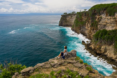 A Woman Sitting on the Edge of a Cliff