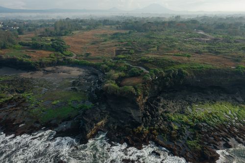 Free Stunning aerial shot showcasing rugged cliffs and lush greenery along a scenic coastline. Stock Photo