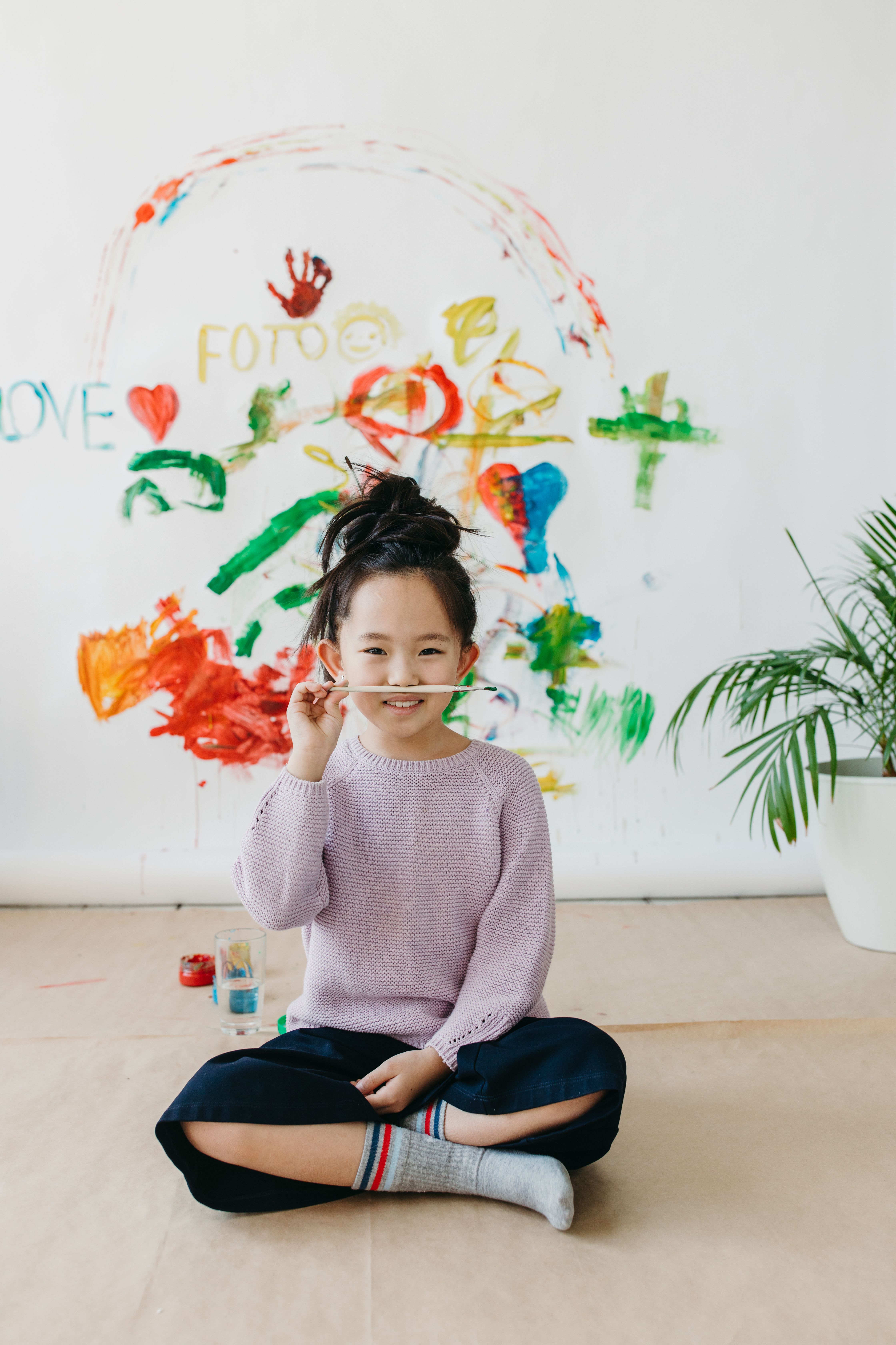 Adorable child painting with colorful brush indoors, sitting happily.