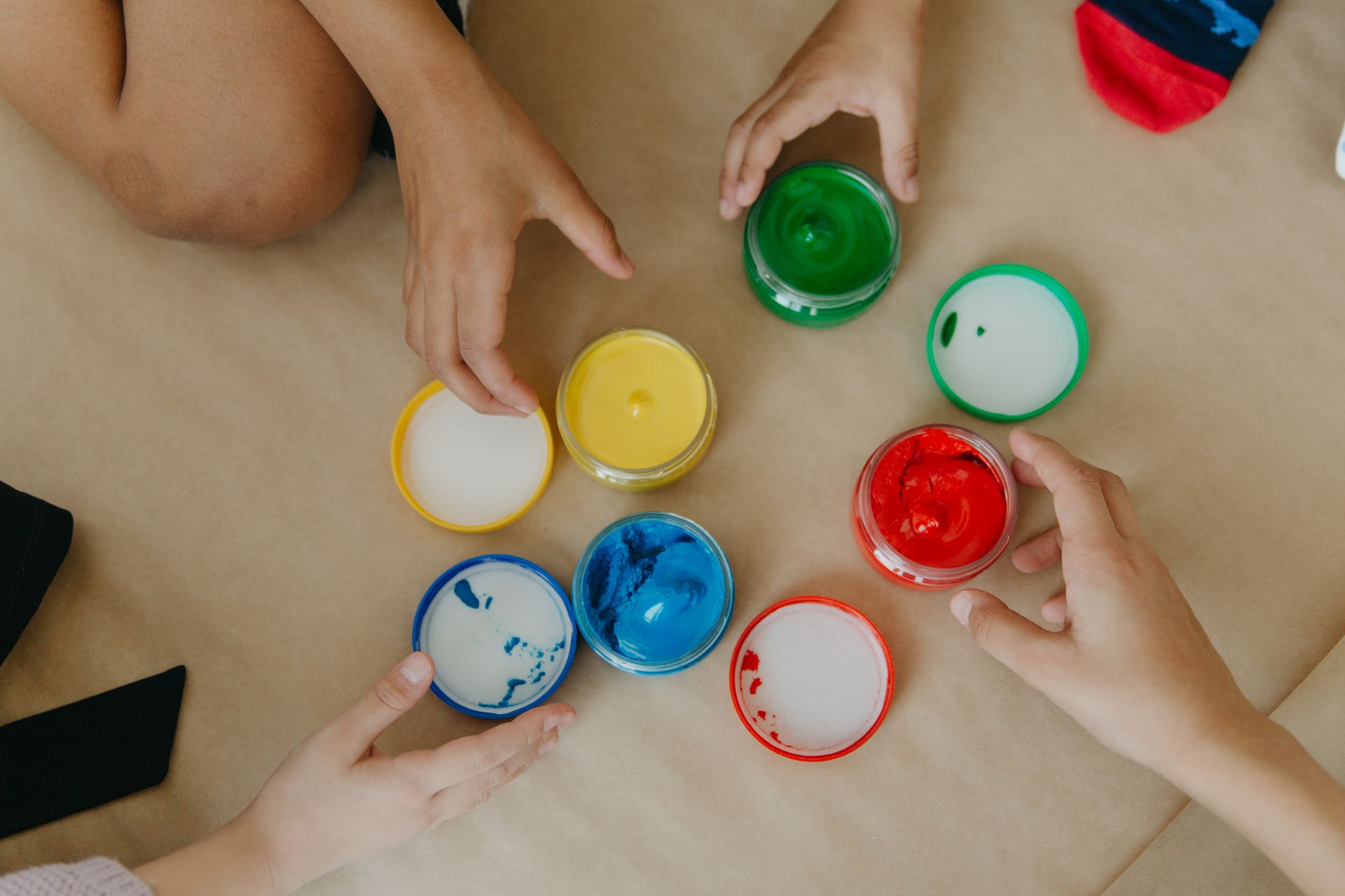 A Close-Up Shot of Children Getting Jars of Paint