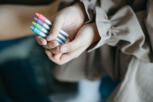 Free Child's hands holding colorful crayons, showcasing creativity in a close-up shot. Stock Photo