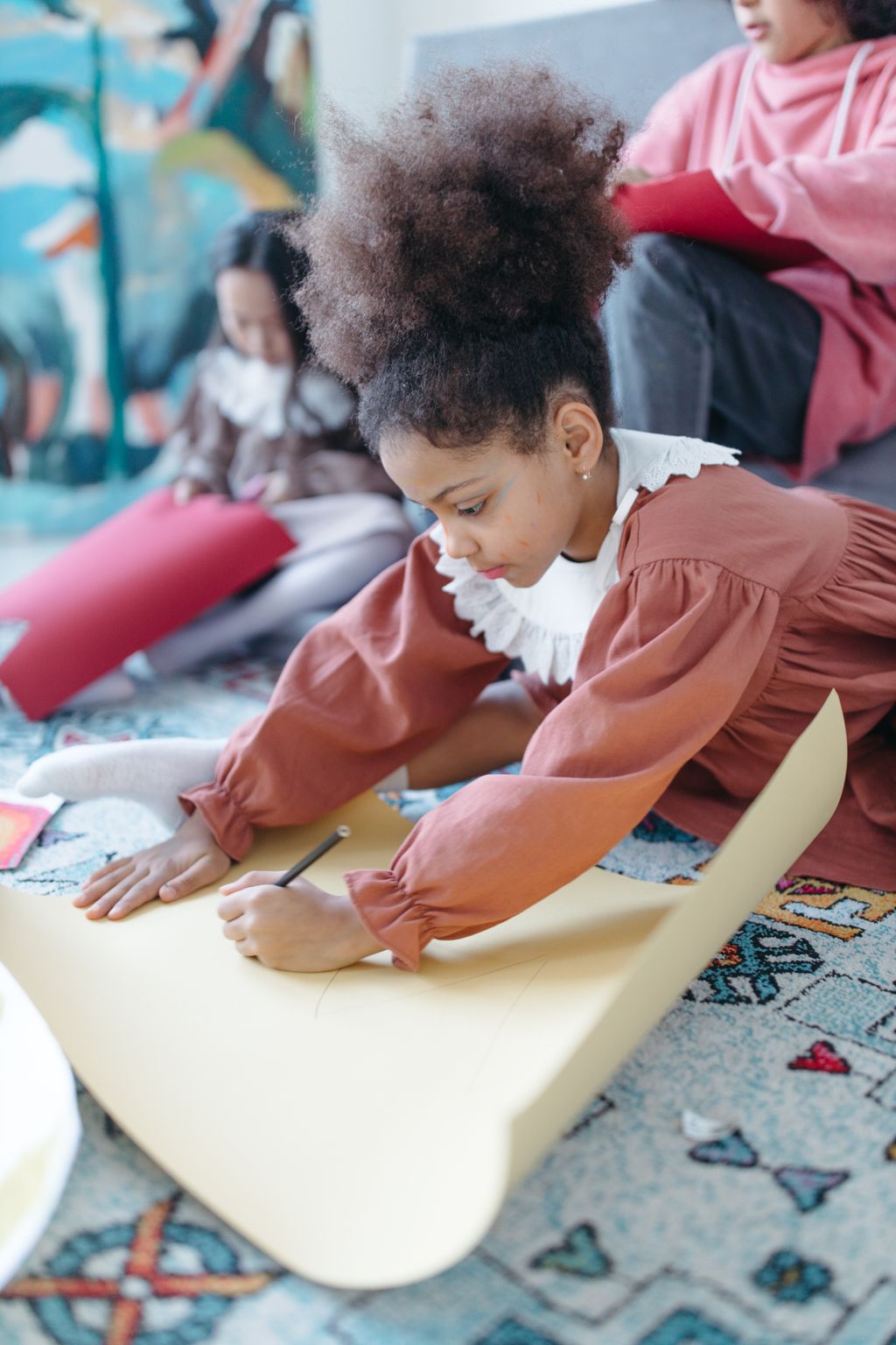 A young girl absorbed in drawing on a large sheet of paper