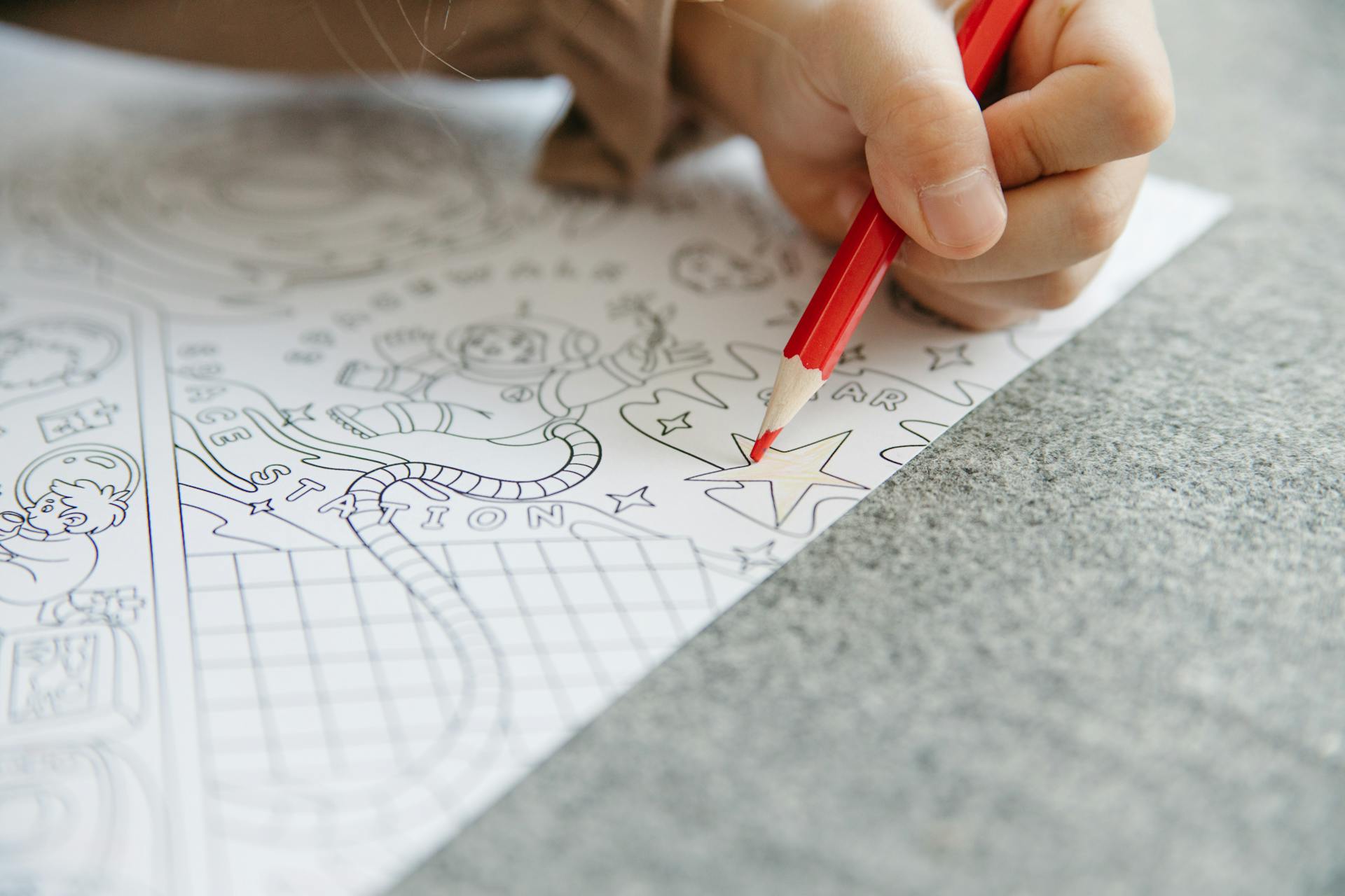 Hand of a Person Coloring a Star on White Paper