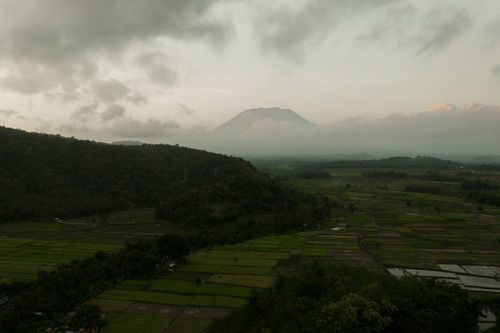 Free Aerial shot of expansive farmland with distant mountains under a cloudy sky. Stock Photo