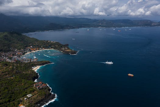 Aerial shot of the Bali coastline with lush greenery and tranquil ocean waters.