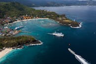 巴厘岛海岸线的令人惊叹的鸟瞰图，展示了晶莹剔透的蓝色水域上的渡轮