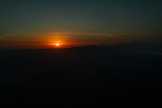 A breathtaking sunrise over silhouetted mountains, showcasing a serene natural landscape.