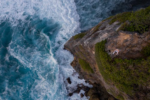 Aerial Photography of a Man Sitting on Rocky Cliff