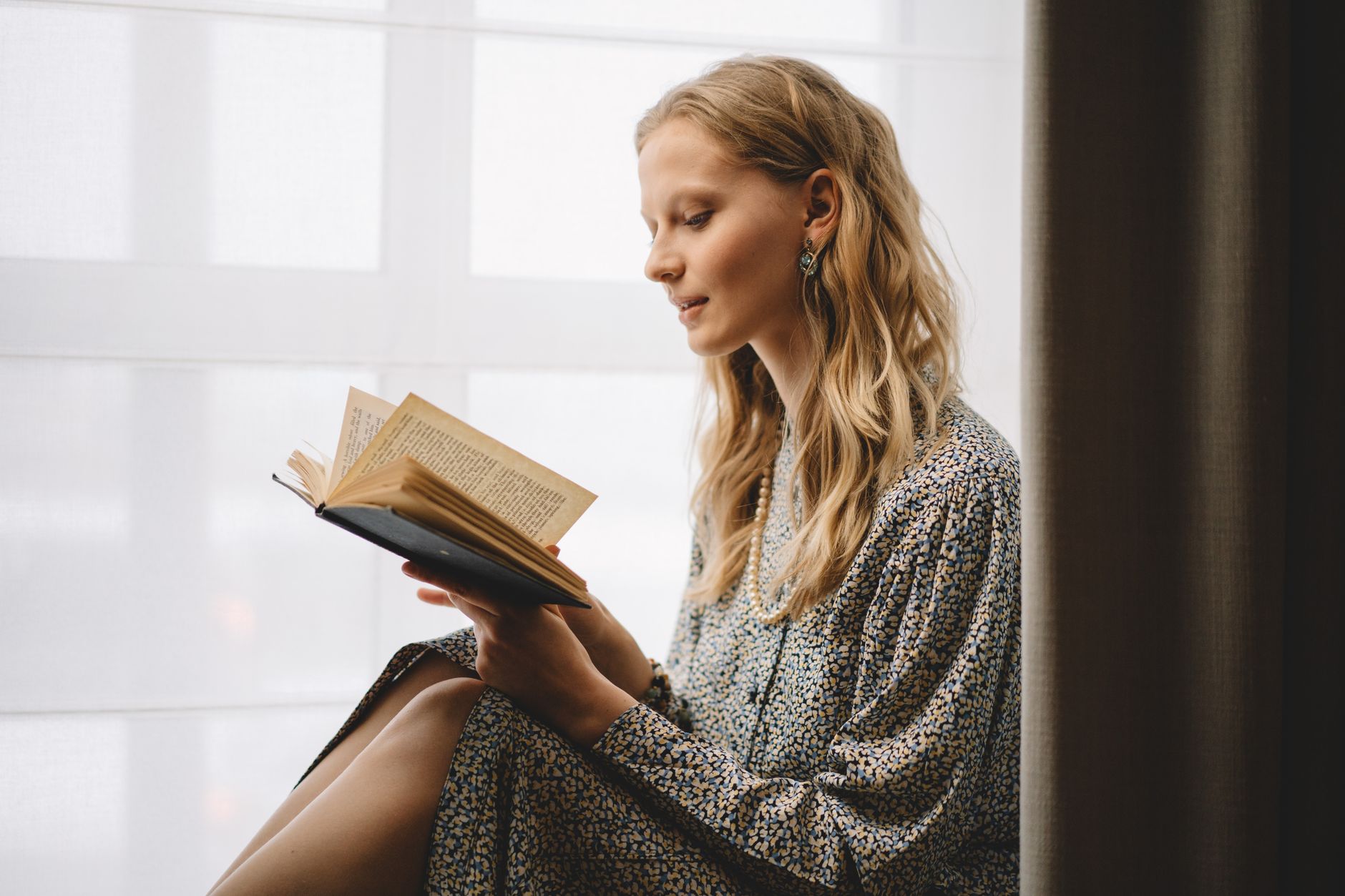 A serene moment of a woman enjoying a book by a softly lit window indoors.. serene, moment, woman