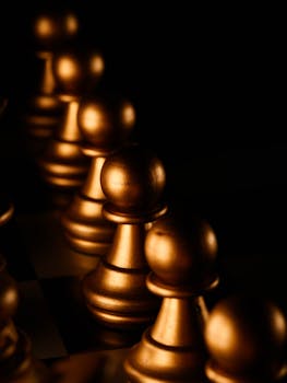 Close-up of golden chess pawns lined up on a chessboard inducing a strategic feel.