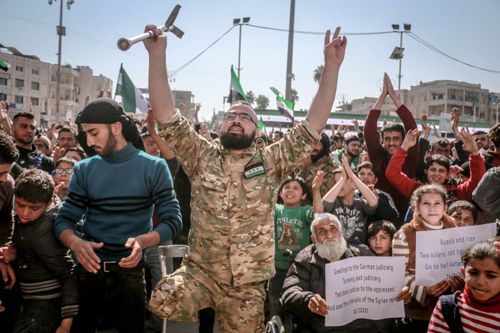 Free Crop ethnic activist with walking stick showing shocker gesture among citizens with placards during manifestation in town Stock Photo