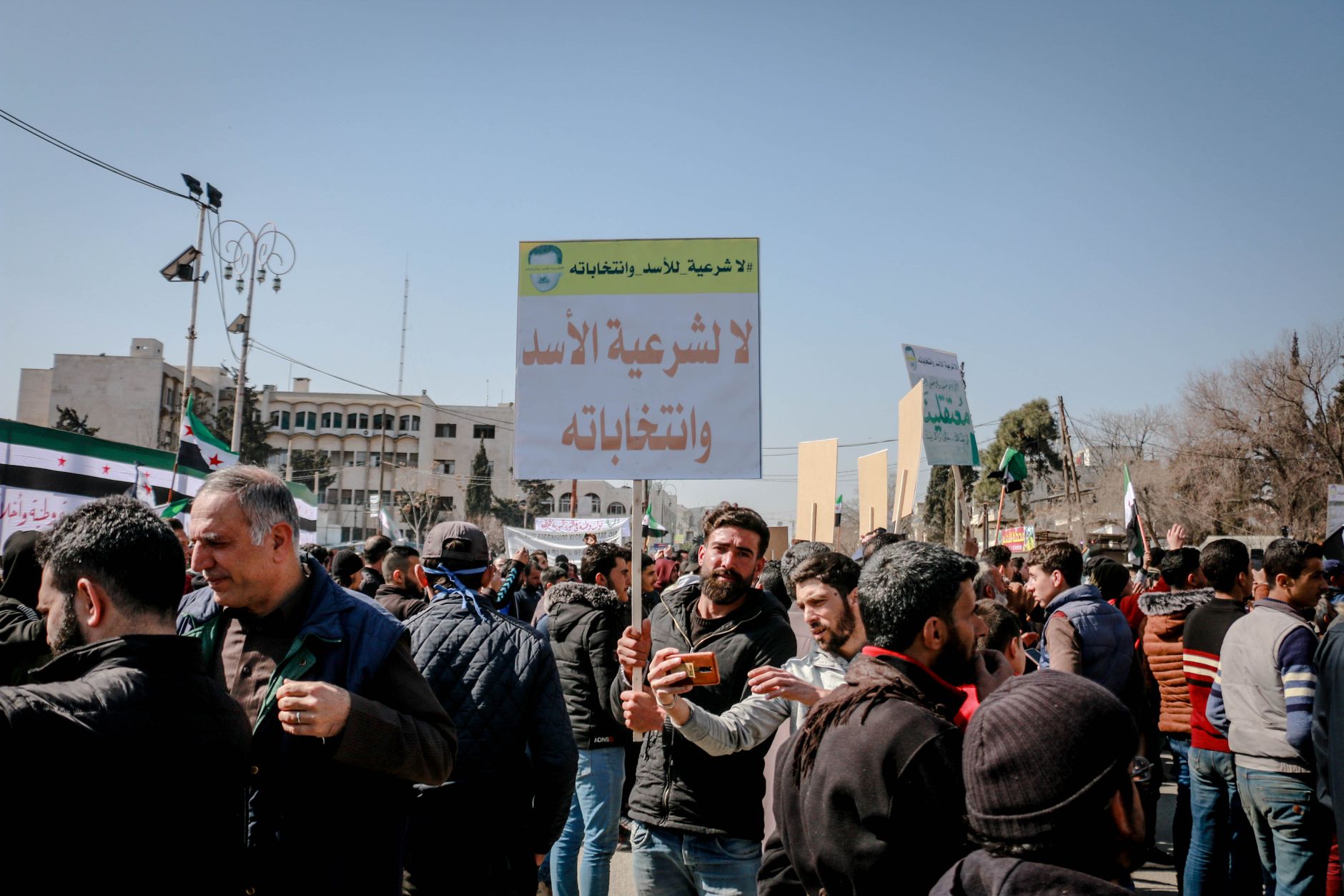 Unrecognizable Arab male activists with inscriptions on placards during strike in town under light sky