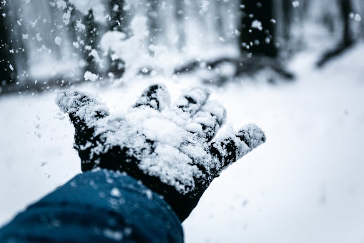 White Snow Falling On A Person's Hand