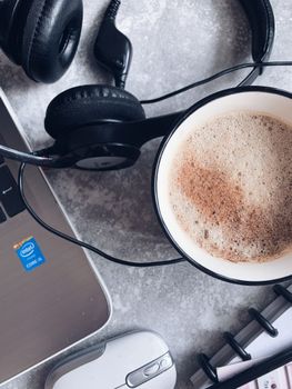 Top view of headphones placed with laptop coffee and notepad for remote work