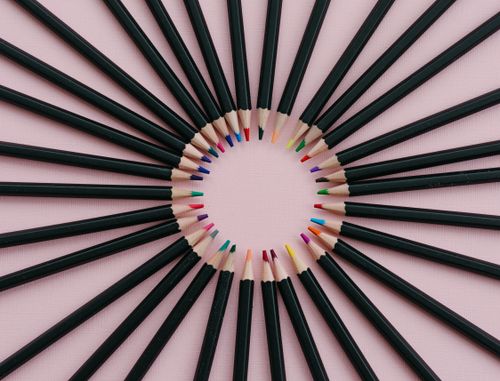 Free Artistic arrangement of colored pencils fanned out on a pink surface, creating a radial pattern. Stock Photo