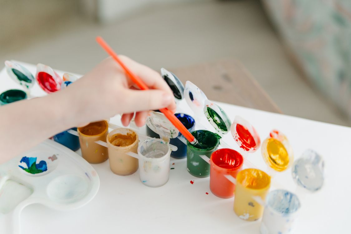 Free A child paints using a colorful watercolor palette, fostering creativity and fun. Stock Photo