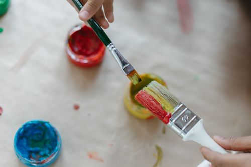 Free Close-up of hands using vibrant paints and brushes, fostering creativity. Stock Photo