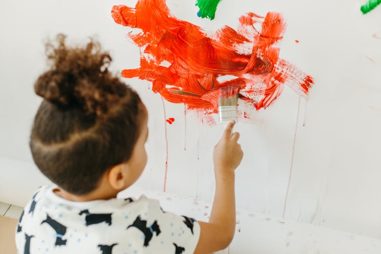 A Young Boy Painting On The Wall