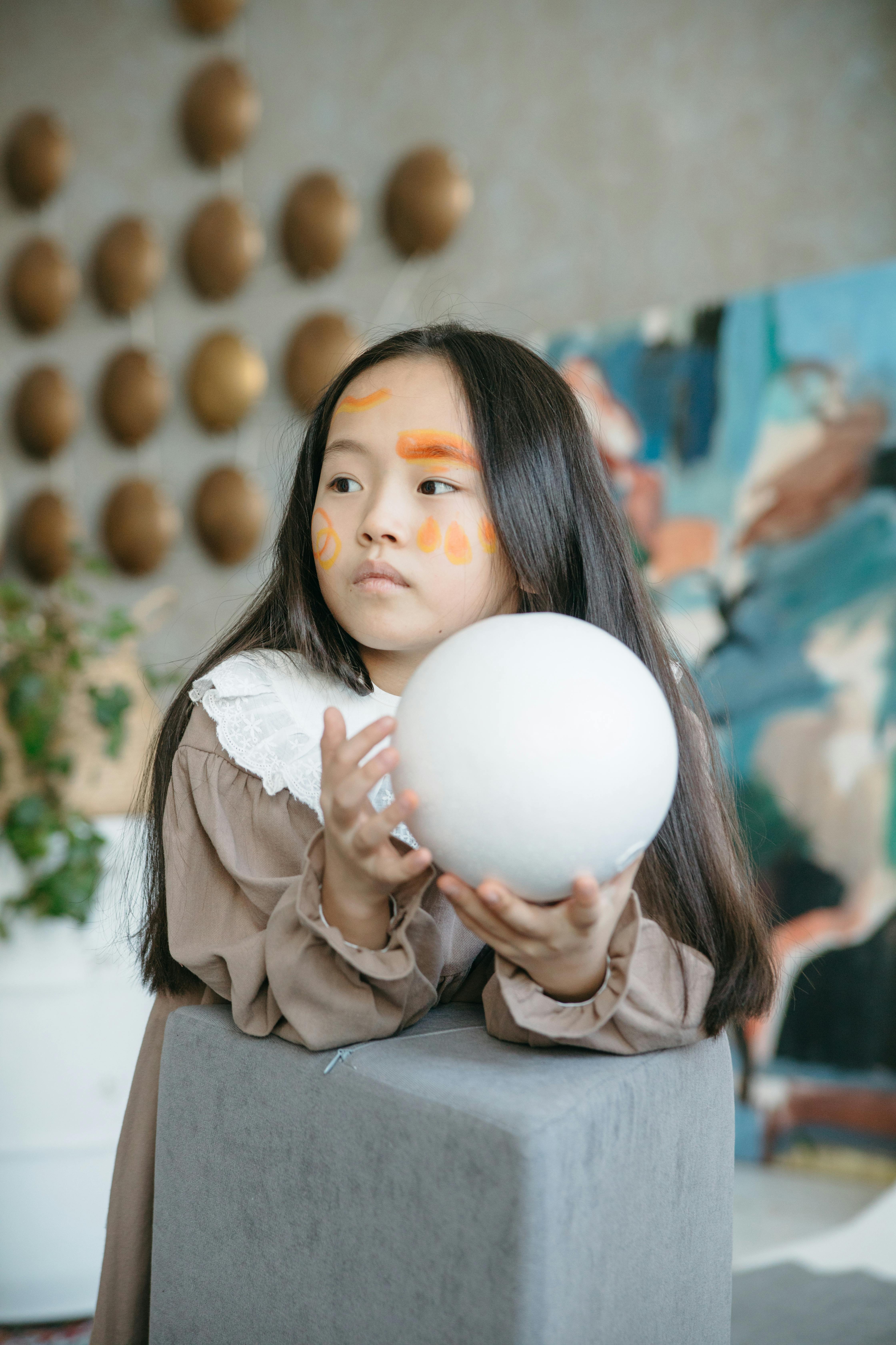 a girl with face paint holding white ball