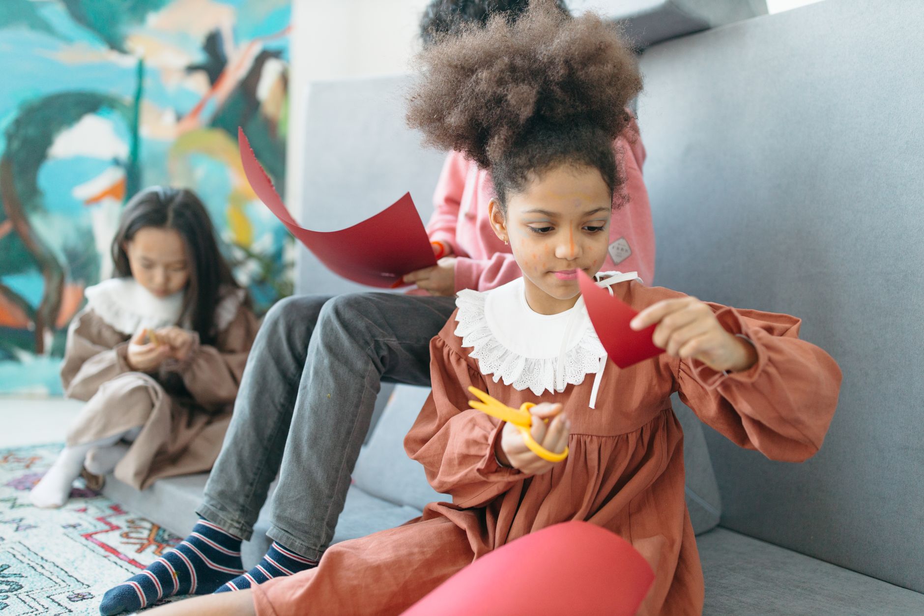 Young children engaged in crafting activities with colorful paper indoors, fostering creativity.