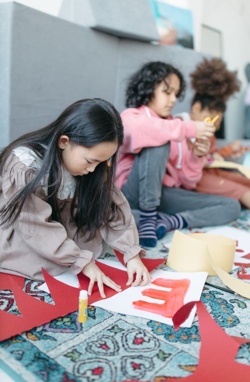Free Children in a classroom setting creating colorful art projects with paper and glue. Stock Photo