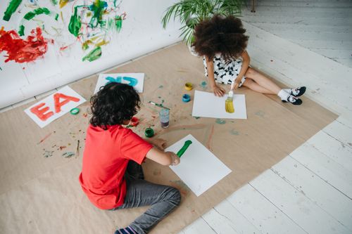 Free Two children painting together indoors, expressing creativity and joy through art. Stock Photo
