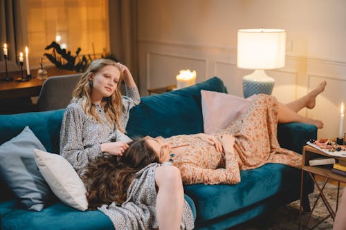 Women Wearing Dresses Relaxing on a Blue Sofa