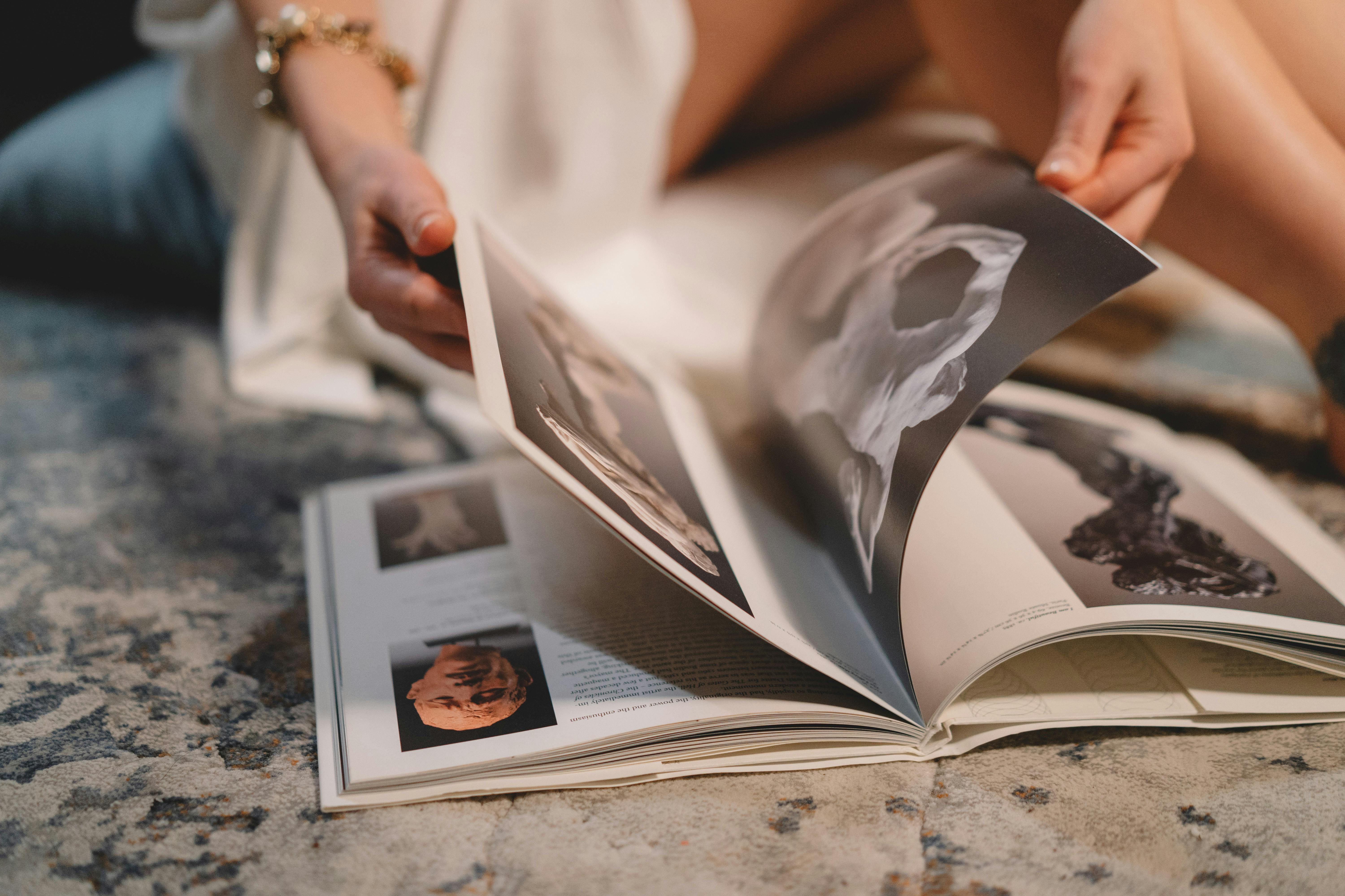 anonymous woman turning page of magazine sitting on couch