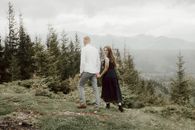 Man and Woman Holding Hands While Walking on Green Grass Field