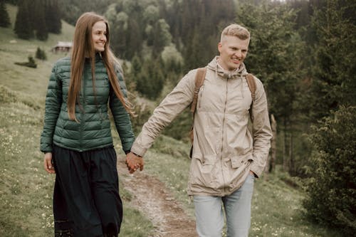 A Sweet Couple Walking on a Grass Field while Holding Each Others Hand