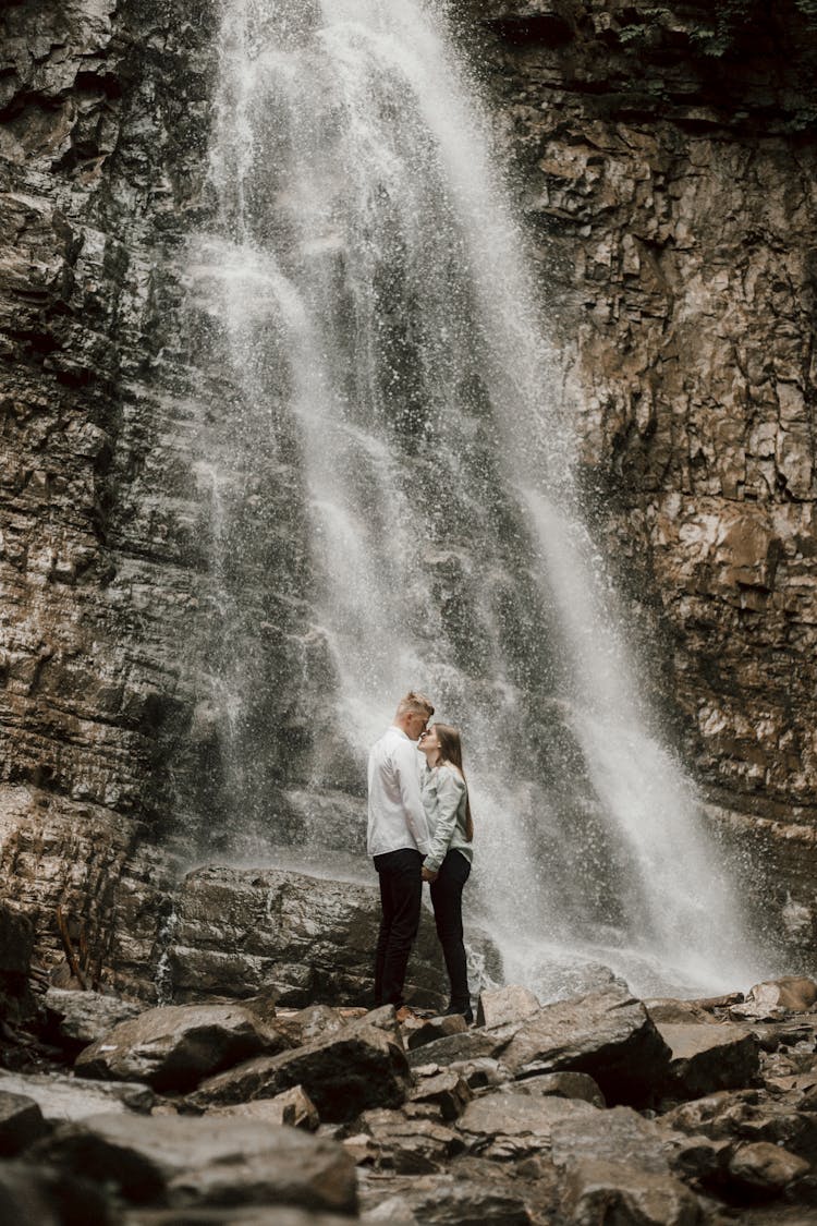 A Couple Kissing Near A Waterfall