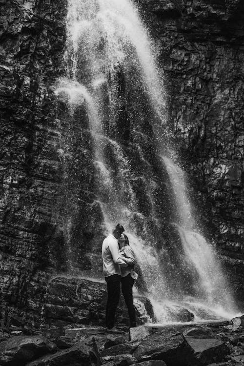 Black and White Photo of Couple Kissing under Waterfall