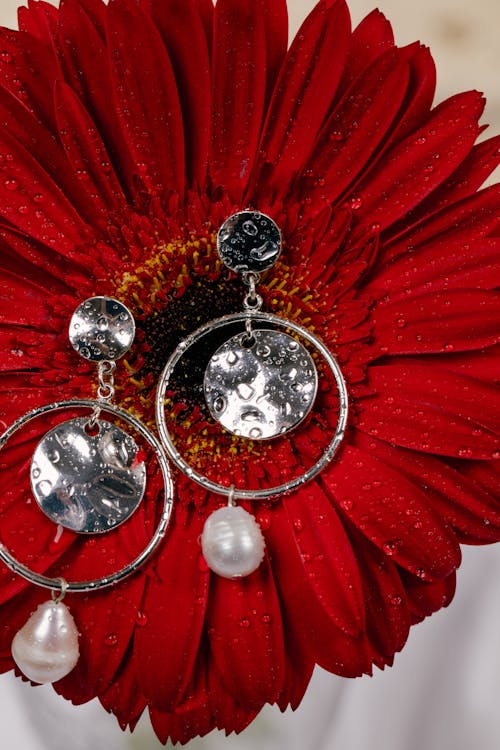 Close-Up Photo of Silver Earrings on Top of a Red Flower