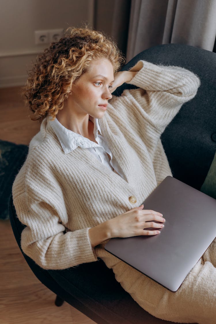 Woman Sitting In Chair With Laptop In Her Knees