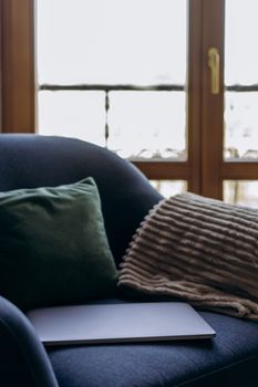 A quiet, sunlit room with a laptop on a sofa chair, perfect for relaxation.
