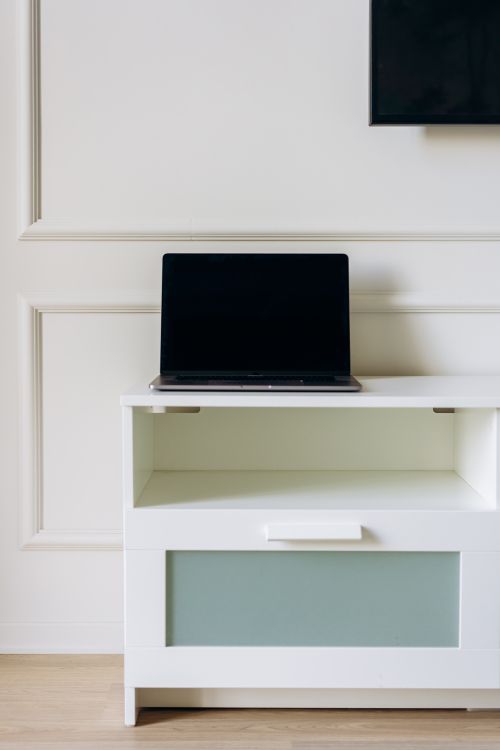 Free A sleek laptop displayed on a white modern cabinet in a minimalist home setting. Stock Photo