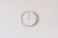 Round Analog Wall Clock With Gold Trim on White Wall