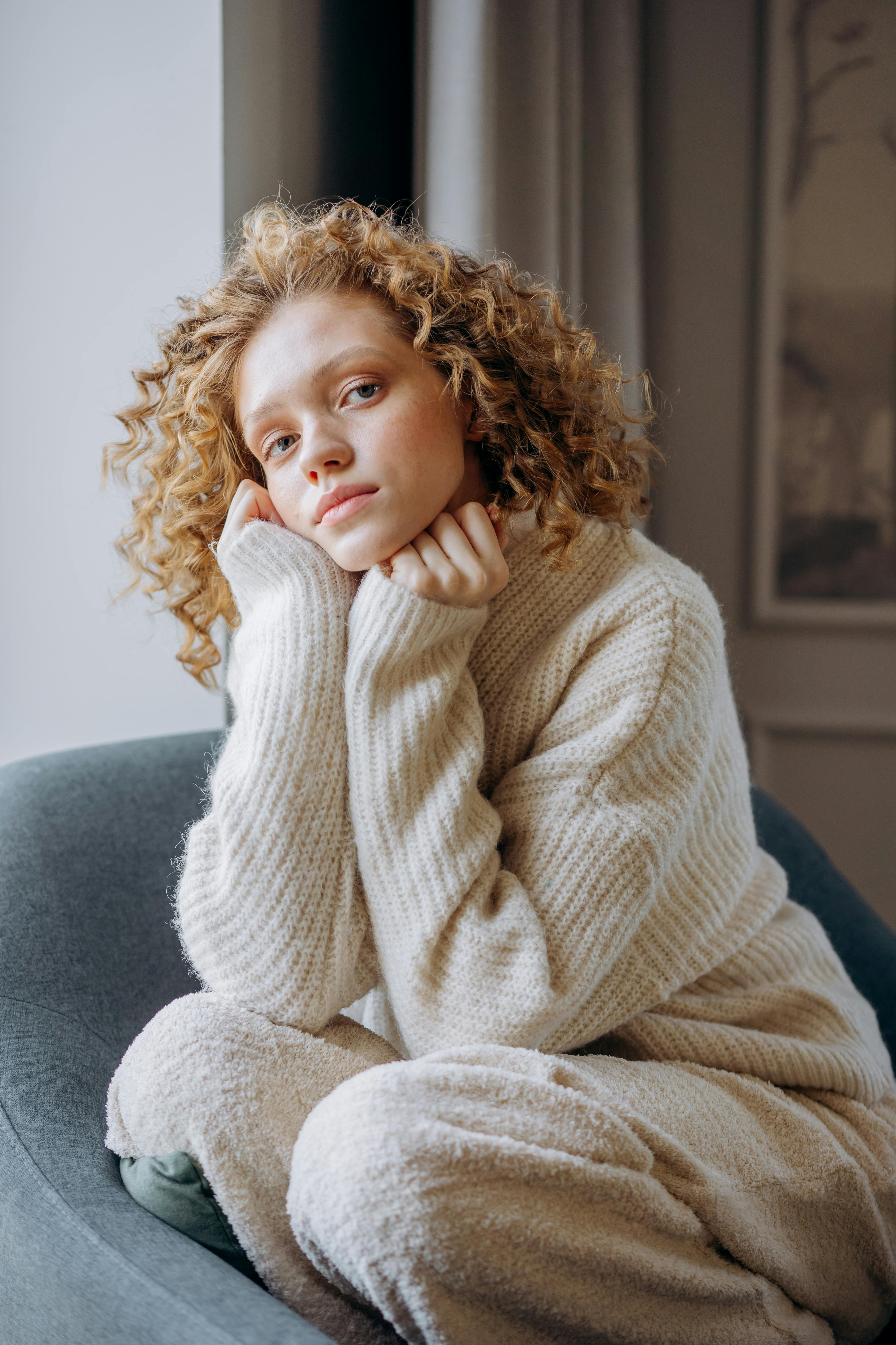 woman in white knit sweater sitting on gray sofa