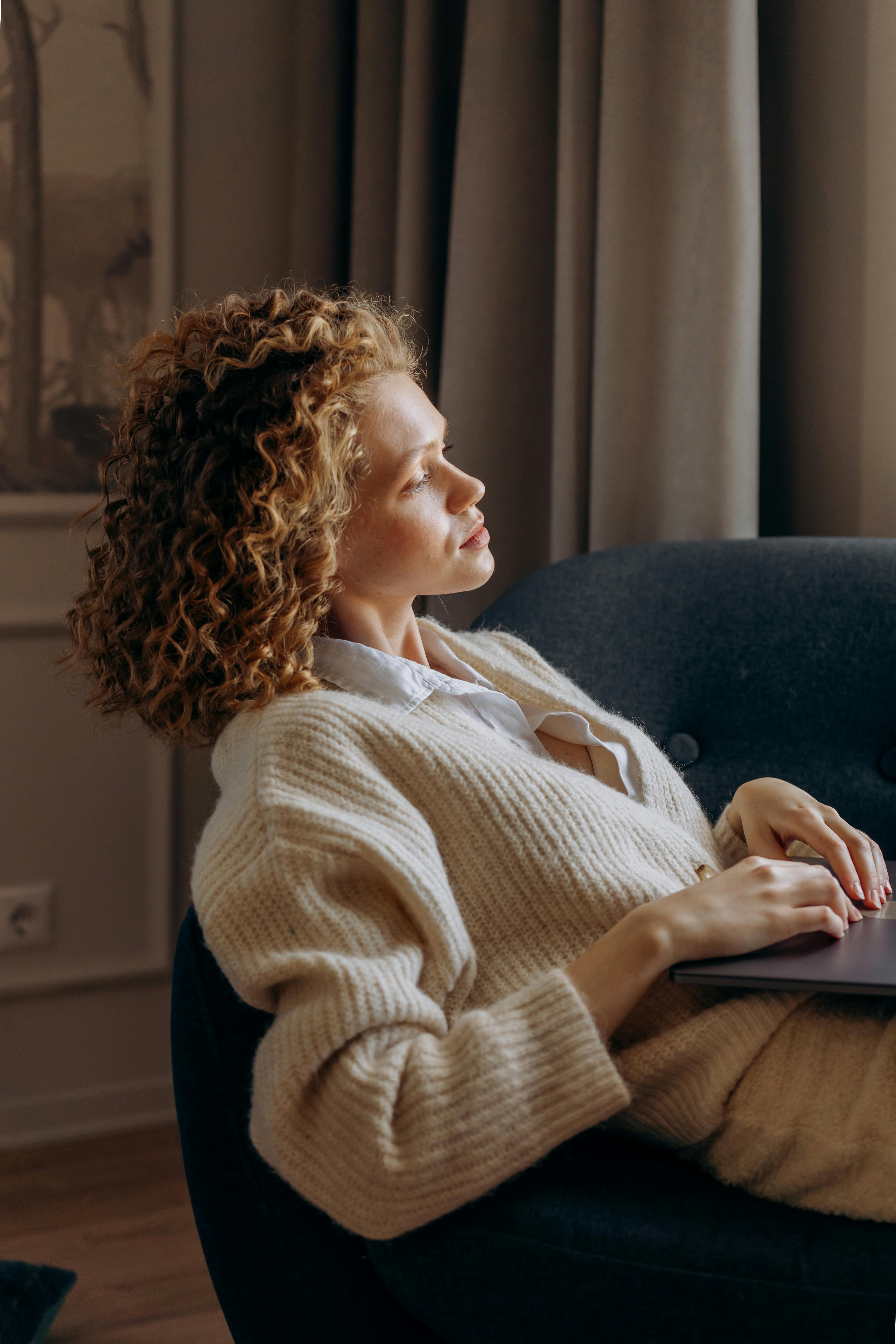 woman in white long sleeves sweater sitting on sofa