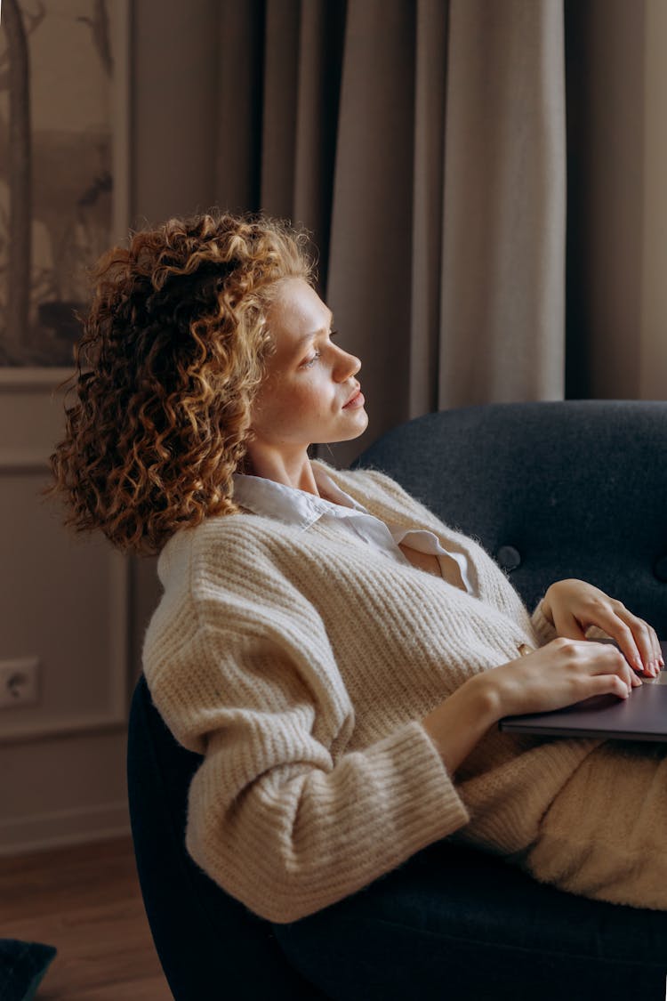 Woman In White Long Sleeves Sweater Sitting On Sofa