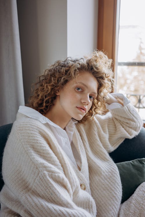 A Woman with Curly Hairs Wearing a Knitted Sweater